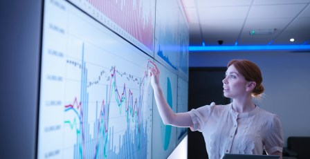 Businesswoman studying graphs on screens