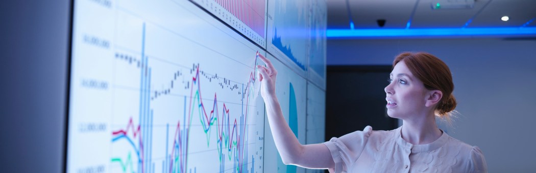Businesswoman studying graphs on screens